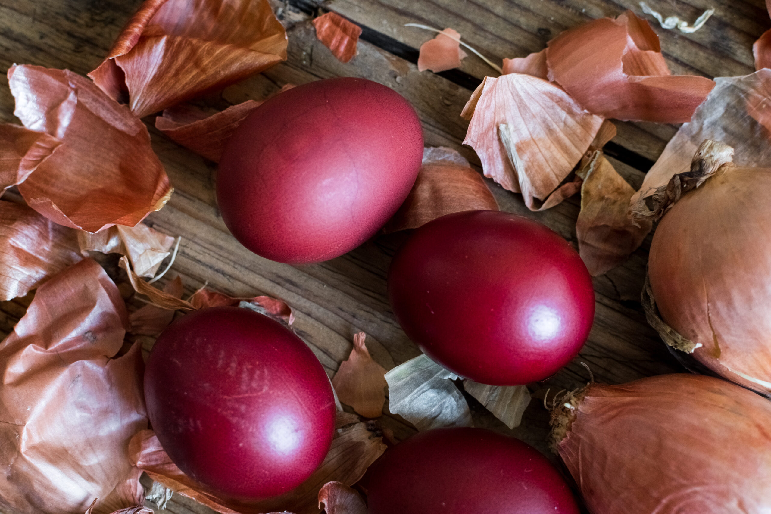 Dyed Easter eggs painted with natural dye onion on rustic wooden background. Process of dyeing eggs with natural paints for Easter. Natural ecological staining with food coloring. Top view.