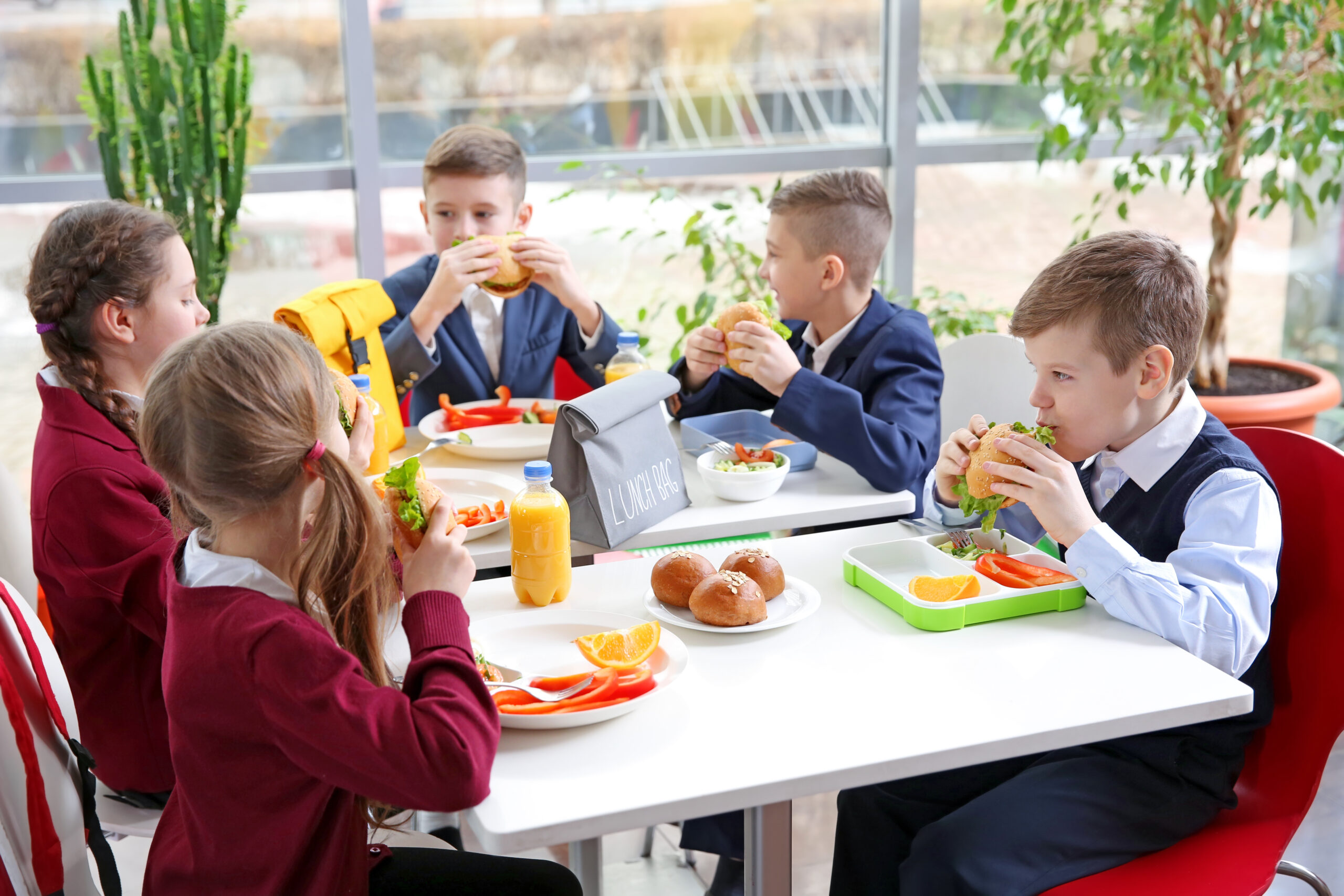 Children sitting at cafeteria table while eating lunch